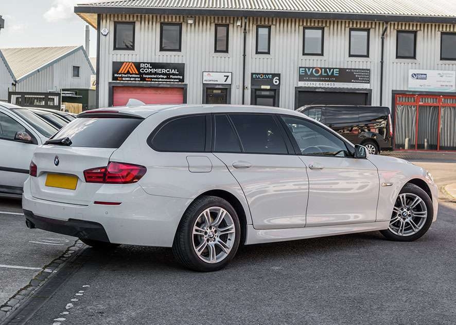 White BMW 5 series with tinted windows from rear