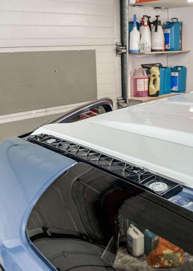 White vinyl wrap being heated on roof of Blue Land Rover Defender
