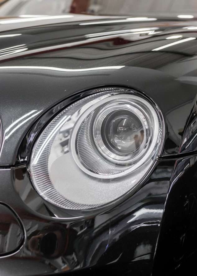 Close up shot of one Bentley Flying Spur car headlight with fog/cloudiness removed after headlight restoration