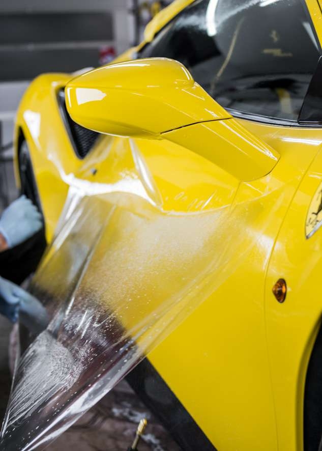 Paint protection film (PPF) being applied to door of yellow Ferrari 488 Pista