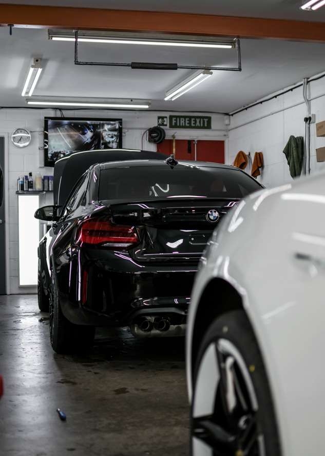 Rear of black BMW M2C during paint protection film (PPF)