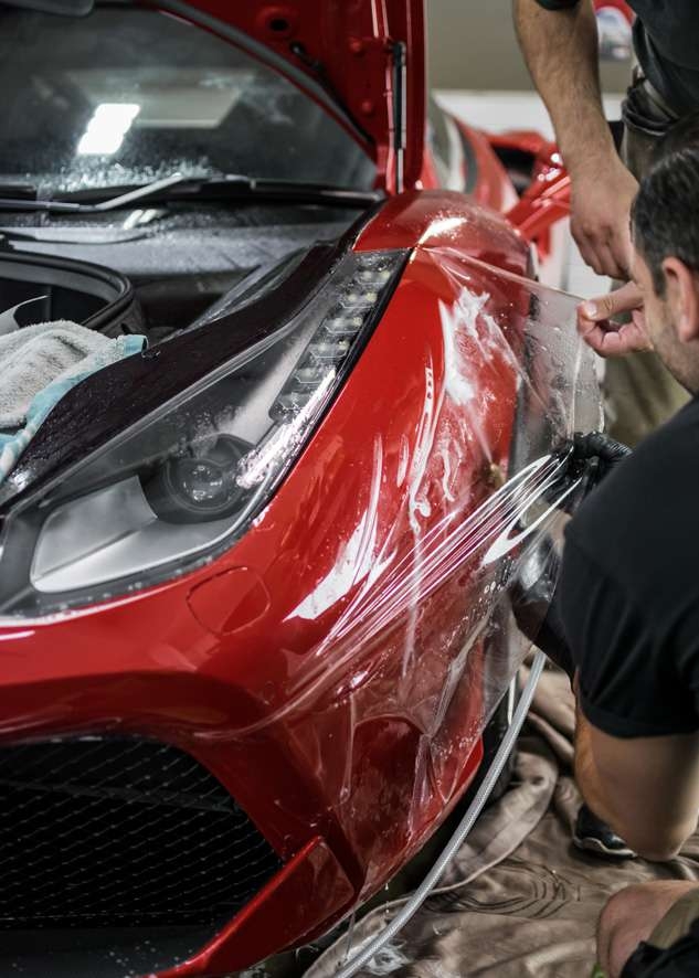 Paint protection film (PPF) being applied to red Ferrari 458 GTB front bumper