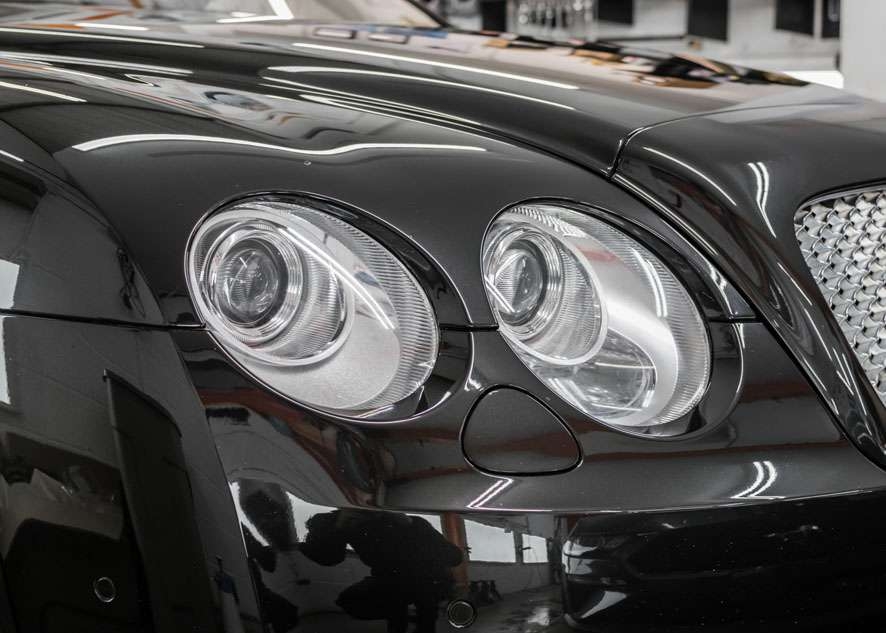 Close up shot of two Bentley Flying Spur car headlights with fog/cloudiness removed after headlight restoration