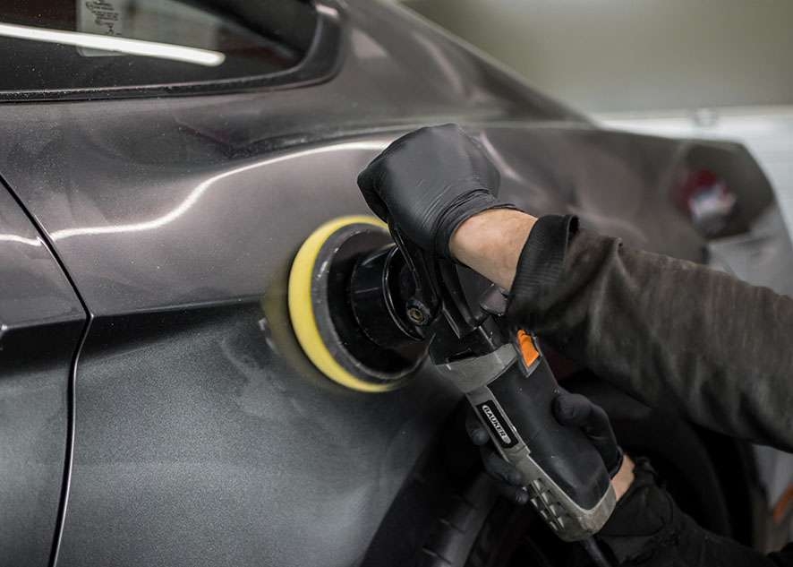 Grey Mustang GT car being machine polished in gloves