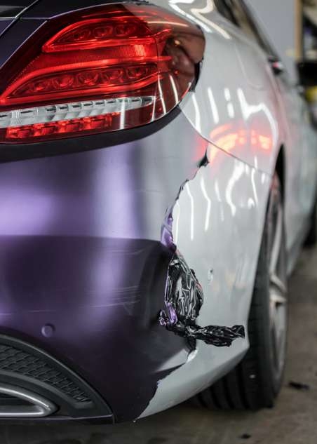Purple vinyl wrap being removed from car grey Mercedes C Class