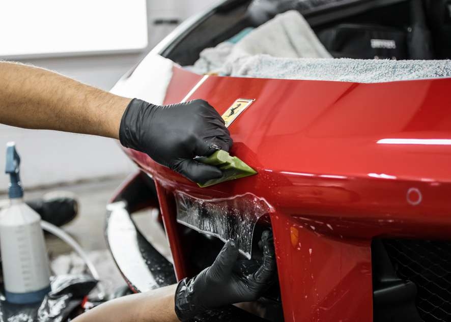 Paint protection film (PPF) being applied to front bumper of red Ferrari 458 GTB