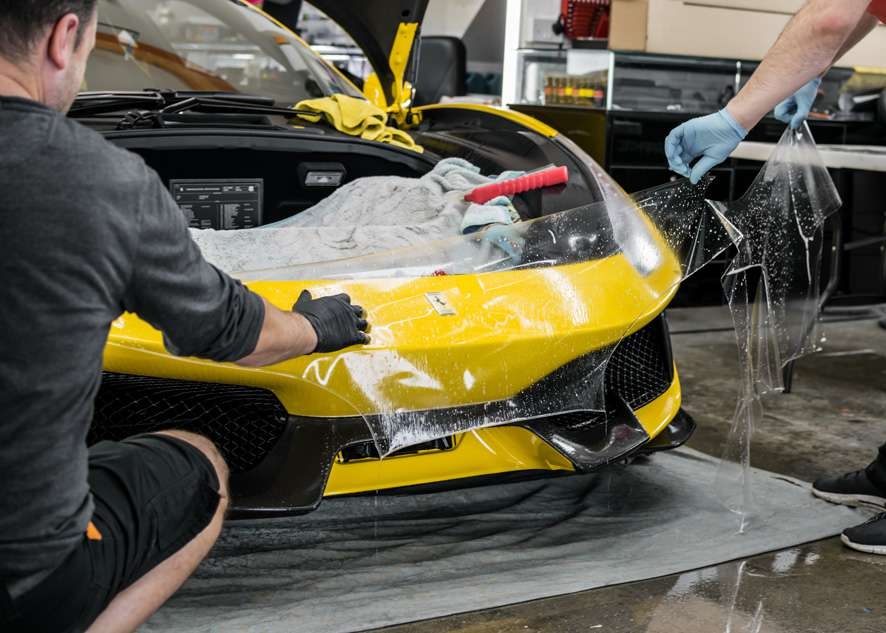 Paint protection film (PPF) being applied to front bumper of yellow Ferrari 488 Pista